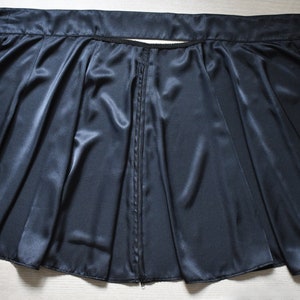 Peut inclure: Une jupe portefeuille en satin noir avec une fermeture &eacute;clair et une longue ceinture &agrave; nouer &agrave; la taille.
