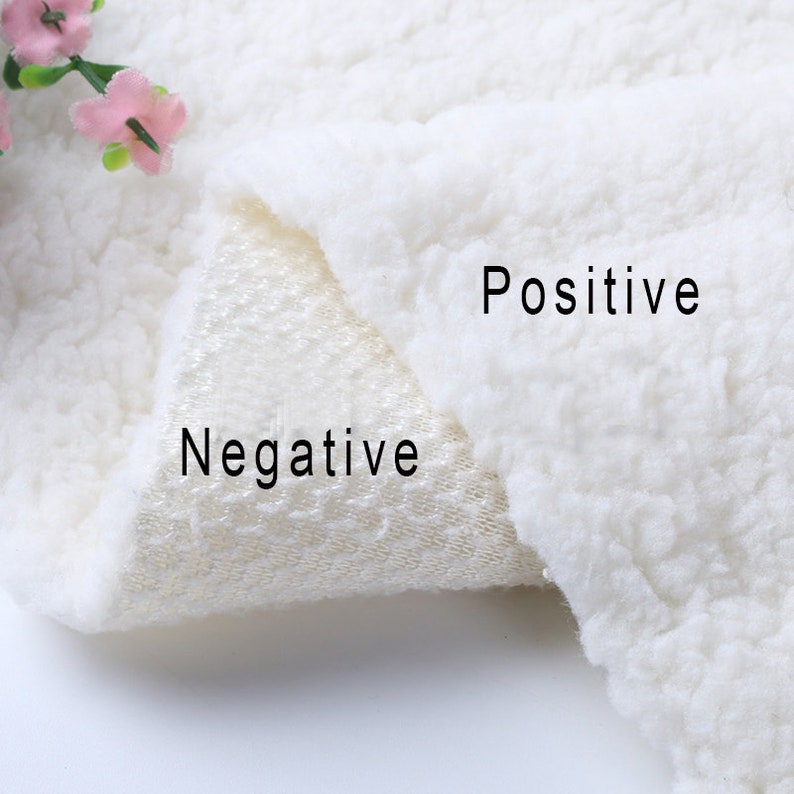 May include: Close-up of a white fabric with a fluffy texture on one side and a smooth, woven texture on the other. The words "Positive" and "Negative" are labeled on the fabric.
