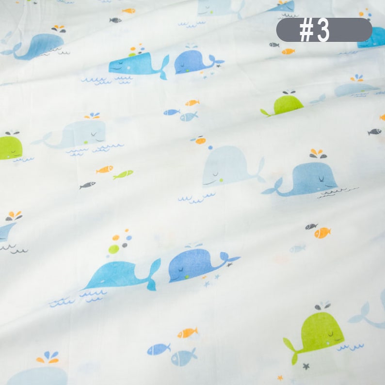 May include: White fabric with a repeating pattern of blue and green whales, orange and blue fish, and white stars. The fabric has the number #3 printed in the top right corner.
