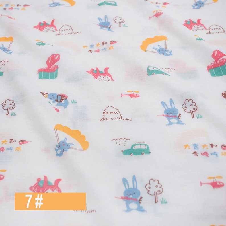 May include: White fabric with a repeating pattern of colourful cartoon bunnies, helicopters, cars, and other whimsical illustrations. The text "大吉大利今晚吃鸡" is repeated throughout the fabric. The number "7#" is written in orange at the bottom of the image.