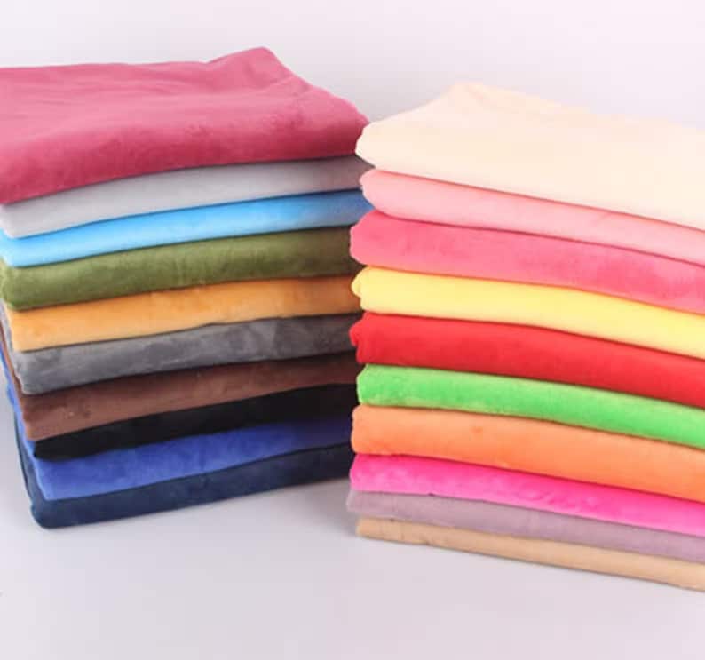May include: A stack of fabric swatches in various colors, including pink, blue, green, orange, and brown. The fabric is soft and plush, and it would be perfect for crafting projects or home decor.