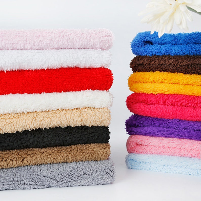 May include: A stack of 10 different colored fluffy fabric swatches. The colors are pink, white, red, white, beige, black, brown, gray, light blue, and pink.