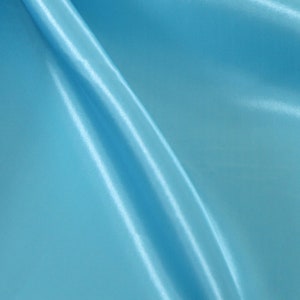 May include: A smooth, light blue fabric with a subtle sheen. The fabric is folded and draped, creating soft, flowing lines.
