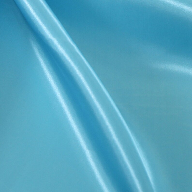 May include: A smooth, light blue fabric with a subtle sheen. The fabric is folded and draped, creating soft, flowing lines.
