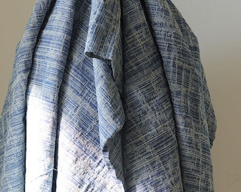 May include: A blue and white patterned fabric with a textured weave. The fabric is folded and draped, showing the texture and pattern.