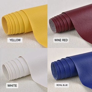 May include: Four rolls of faux leather in different colors: yellow, wine red, white, and royal blue. The leather has a textured surface.