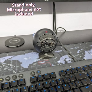 May include: A black microphone stand with a black microphone on top. The stand is on a black surface with a world map design. The text "Stand only, Microphone not included" is visible in the image.