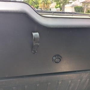 Pode incluir: Uma caneca de cerâmica branca com uma alça preta e o texto "But First, Coffee" em preto, com uma fonte manuscrita. A caneca está sobre uma superfície branca.