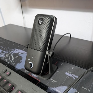 May include: A white ceramic mug with a black handle and the text "But First, Coffee" in a black, handwritten-style font. The mug is on a white surface.