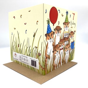 May include: A birthday card featuring a group of meerkats wearing party hats and holding a cake and a present. The card is yellow with green grass and confetti. The text on the card reads "7 today".