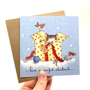May include: A blue Christmas card with a cat peeking out of a gift box with red ribbon and yellow stars. The gift box has a tag that says "Happy Christmas". Two red robins are perched on the gift box and the card says "have a purrfect christmas".