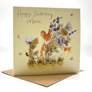 May include: A greeting card with the text "Happy Birthday Mum" features a watercolor illustration of a mouse holding a bouquet of wildflowers. Butterflies and other flowers are scattered around the card, which is set on a brown envelope.