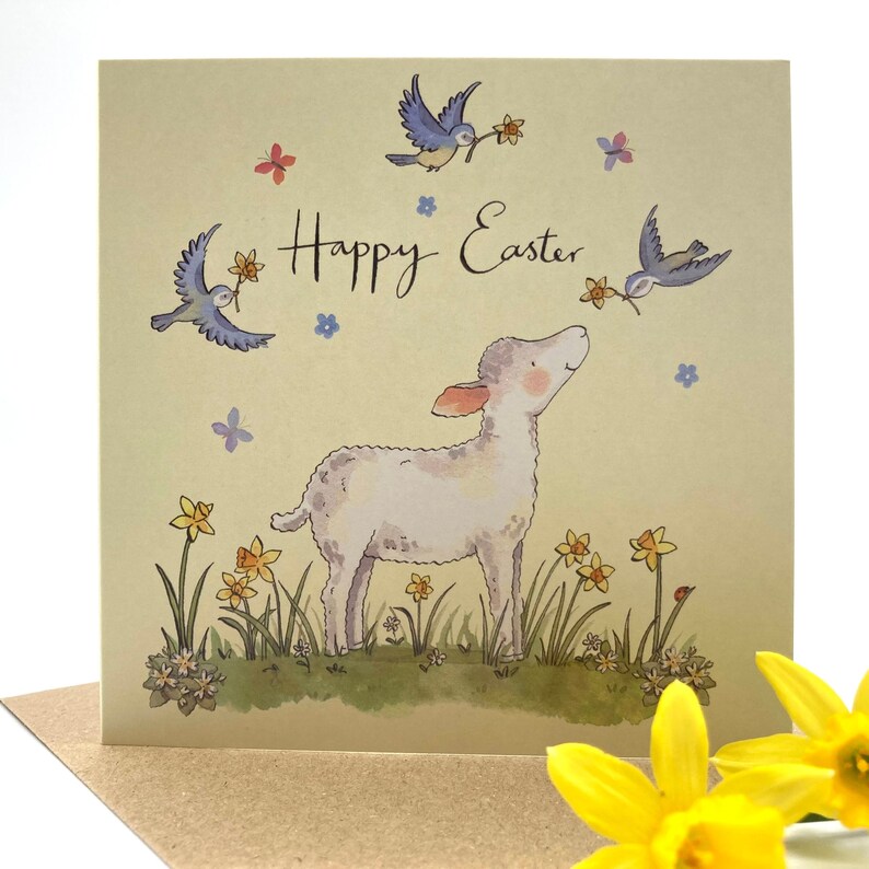 May include: A Happy Easter greeting card with a white lamb standing in a field of yellow daffodils and blue birds flying overhead. The card has a light yellow background with blue and pink flowers scattered around.