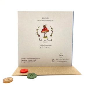 May include: A greeting card with a mushroom and snail illustration. The card reads "Ink and Snail Designs" and "Purrfect Christmas" with the artist's name "By Honor Barton". The card is blank inside for a personal message.