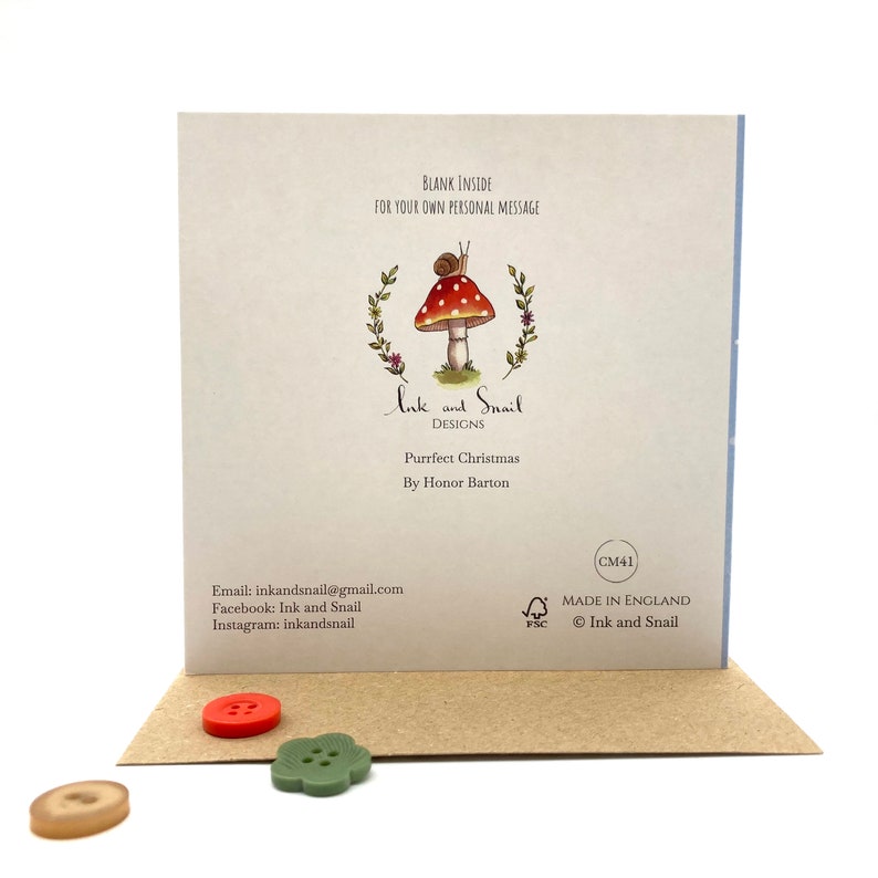 May include: A greeting card with a mushroom and snail illustration. The card reads "Ink and Snail Designs" and "Purrfect Christmas" with the artist's name "By Honor Barton". The card is blank inside for a personal message.