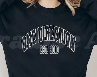 Op de afbeelding: Zwart sweatshirt met witte tekst die "One Direction Est. 2010" zegt.