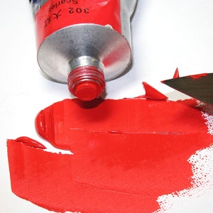 May include: A tube of red acrylic paint with the label "302  Scarlet" squeezed out onto a white surface. A palette knife is used to spread the paint.