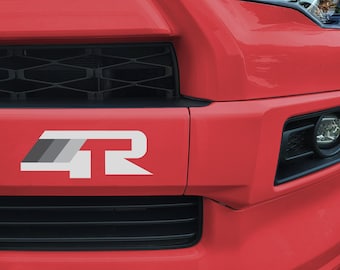 Può includere: Un'auto rossa con una griglia nera e un emblema "4R" bianco sul paraurti anteriore.