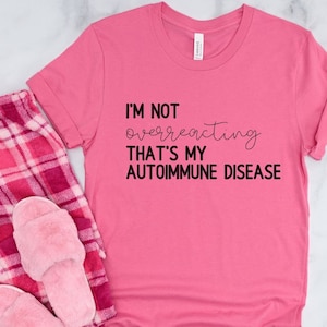 May include: Pink t-shirt with black text that reads "I'm not overreacting that's my autoimmune disease".