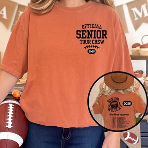 Könnte beinhalten: Ein orangefarbenes T-Shirt mit dem Aufdruck "OFFICIAL SENIOR TOUR CREW 2025" auf der Vorderseite. Das Shirt hat auch eine Football-Grafik. Ein kleineres Bild zeigt die Rückseite des Shirts mit "SENIOR WILDCAT 2025" und einer Liste.