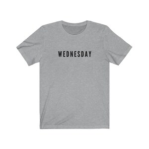 Peut inclure: Un t-shirt gris chin&eacute; avec le mot "WEDNESDAY" imprim&eacute; en noir sur le devant.