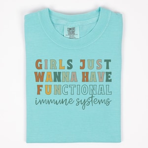 May include: A light blue t-shirt with the text "Girls Just Wanna Have Functional Immune Systems" in colorful letters.