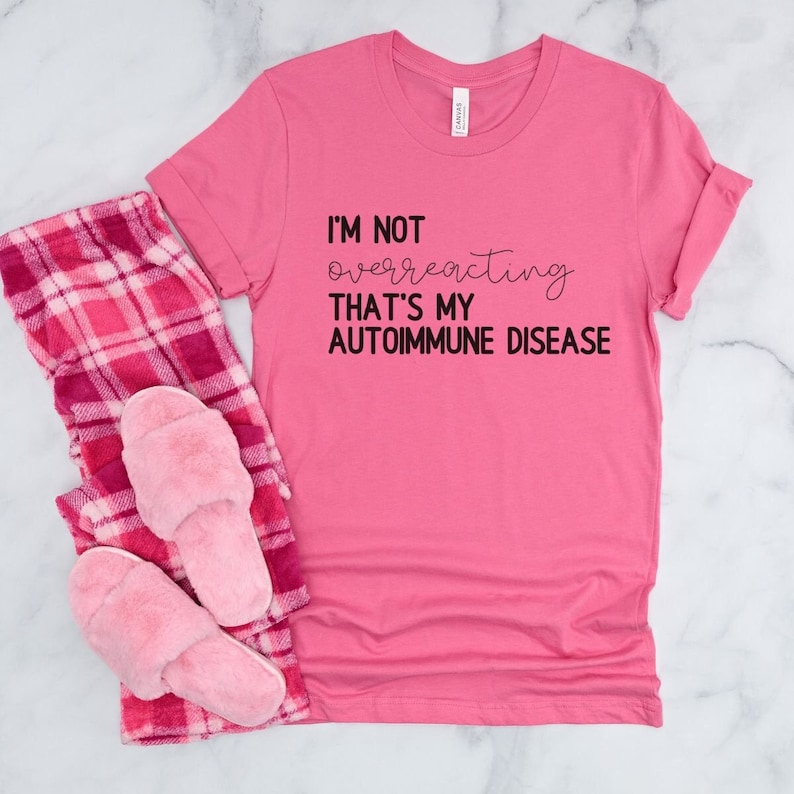 May include: Pink t-shirt with black text that reads "I'm not overreacting that's my autoimmune disease".