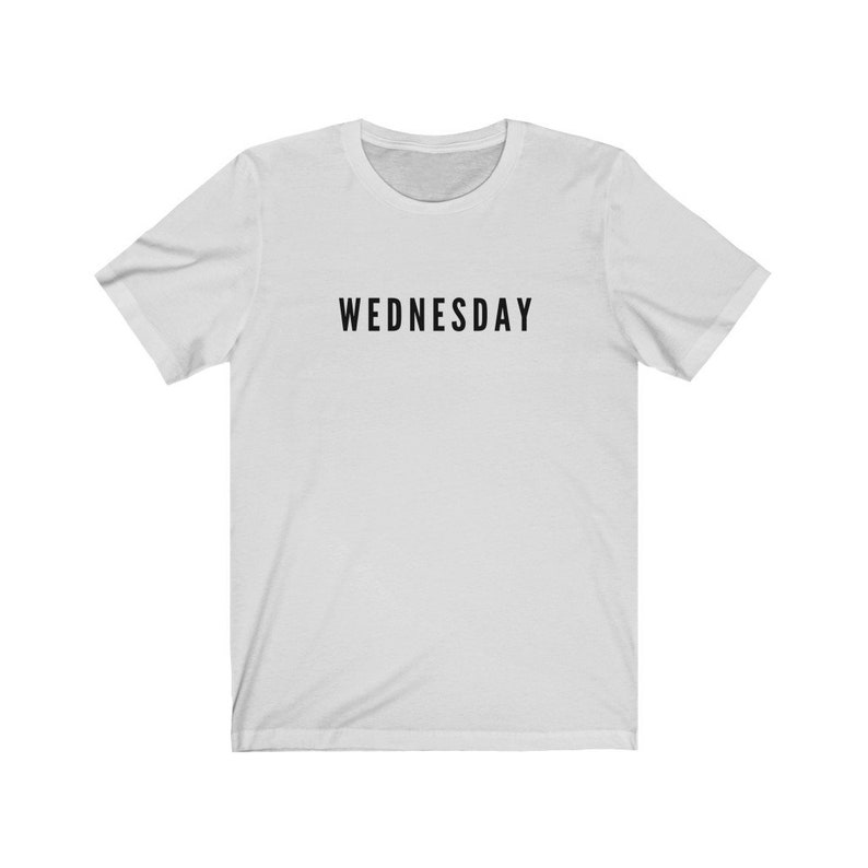Peut inclure: T-shirt blanc avec un texte noir qui dit "WEDNESDAY" sur le devant.