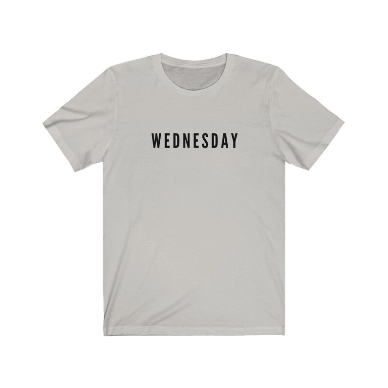 Peut inclure: Un t-shirt gris clair avec le mot "WEDNESDAY" imprim&eacute; en noir sur le devant.