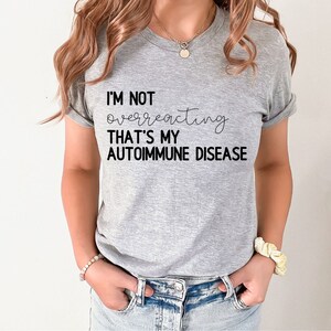 May include: A gray t-shirt with the text "I'm not overreacting that's my autoimmune disease" printed in black.