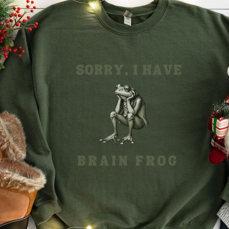 May include: A green sweatshirt with the text "Sorry, I have Brain Frog" and a cartoon frog with a thoughtful expression.