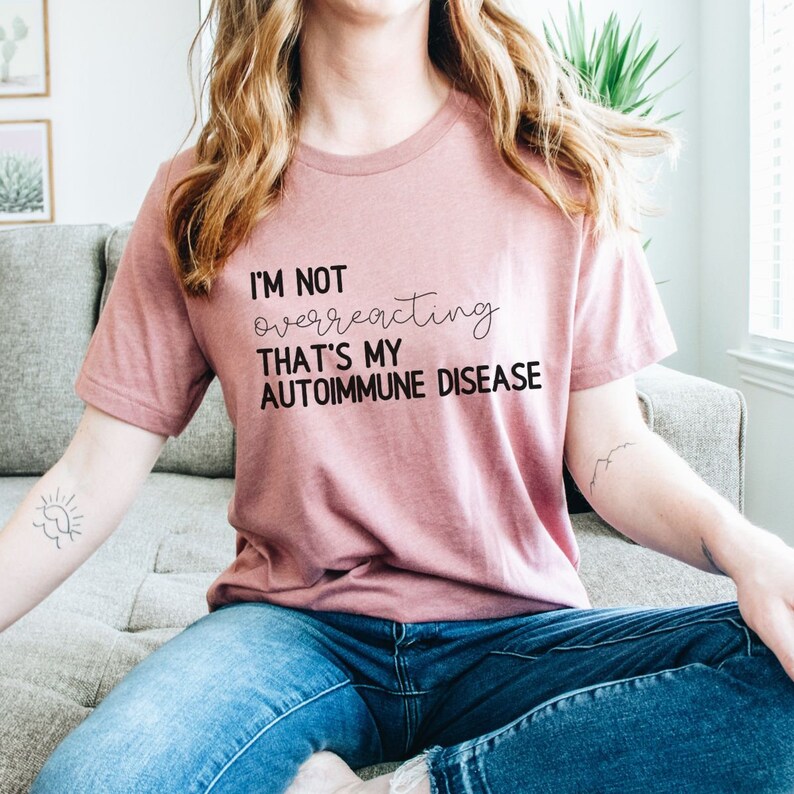 May include: A pink t-shirt with the text "I'm not overreacting that's my autoimmune disease" printed in black.