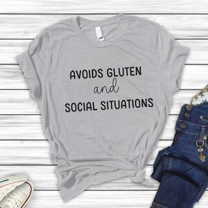 May include: Grey t-shirt with the text "Avoids Gluten and Social Situations" printed on the front.