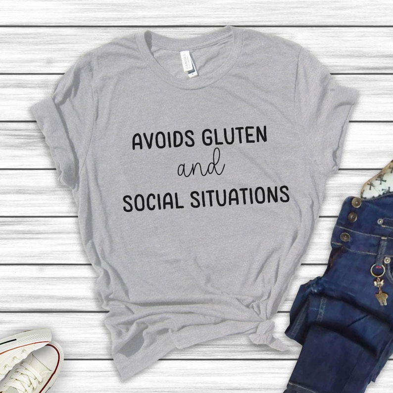 May include: Grey t-shirt with the text "Avoids Gluten and Social Situations" printed on the front.