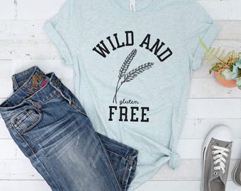 May include: A light blue t-shirt with the text "Wild and Gluten Free" in black lettering. The shirt features a graphic of two wheat stalks.