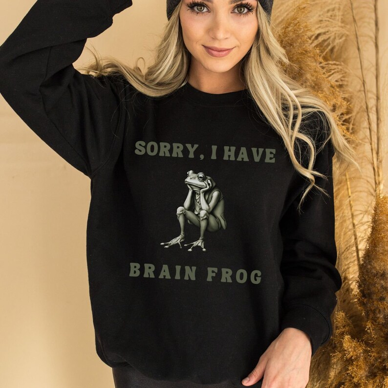 May include: Black sweatshirt with a green frog graphic and the text "Sorry, I have brain frog".