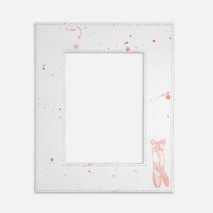 May include: A rectangular white picture frame featuring a stitched border and a pattern of light pink paint splatters. In the bottom right corner, there is a detailed illustration of a pair of ballet slippers with ribbons tied in a bow.