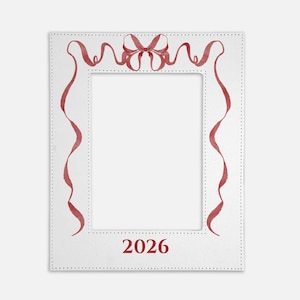 May include: A rectangular white picture frame featuring a decorative red ribbon illustration with a bow at the top center. The frame has a dotted border pattern and the year 2026 printed in red at the bottom center of the frame's lower edge.