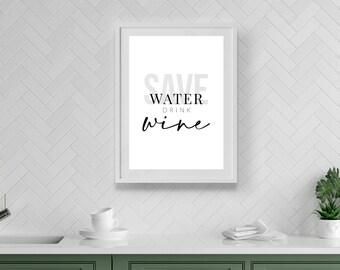 May include: A white framed print with the text "Save Water Drink Wine" hanging on a white subway tile wall in a kitchen. The kitchen has green cabinets and a white countertop.