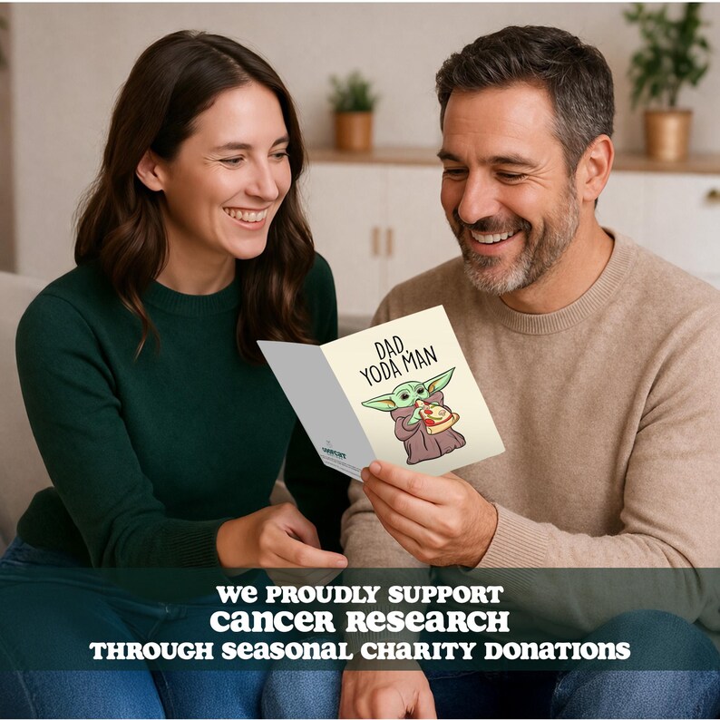K&ouml;nnte beinhalten: Eine Gru&szlig;karte mit dem Text "DAD YODA MAN" und einer Illustration einer Zeichentrickfigur, die eine Pizza h&auml;lt. Die Karte wird von einer Person gehalten. Das Bild enth&auml;lt auch den Text "WE PROUDLY SUPPORT CANCER RESEARCH THROUGH SEASONAL CHARITY DONATIONS."