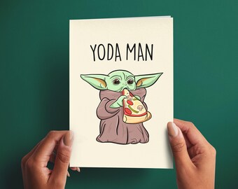 Könnte beinhalten: Eine cremefarbene Grußkarte mit einer Cartoon-Illustration einer grünen Kreatur mit großen Ohren, die eine braune Robe trägt und ein Stück Pizza mit Peperoni und Pilzen isst. Der Text YODA MAN ist in schwarzer Schrift über der Illustration gedruckt.
