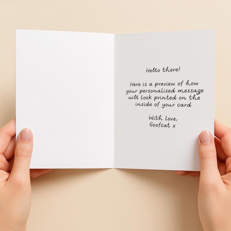 K&ouml;nnte beinhalten: Eine wei&szlig;e Gru&szlig;karte, die aufgeklappt ist und schwarzen gedruckten Text zeigt: Hello there! Here is a preview of how your personalised message will look printed on the inside of your card. With love, Goofcat x.