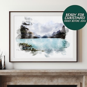 May include: A framed watercolor landscape print depicting a turquoise glacial lake surrounded by dark, jagged mountain peaks and evergreen trees. The artwork features a soft, blended aesthetic with visible paint strokes and a white border.