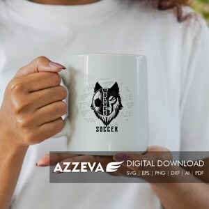 May include: White ceramic mug with a black and white graphic of a wolf's head with a soccer ball inside. The text "WOLVES" is inside the wolf's head and the text "SOCCER" is below the wolf's head. The text "VA" and "AZE" are repeated around the wolf's head.