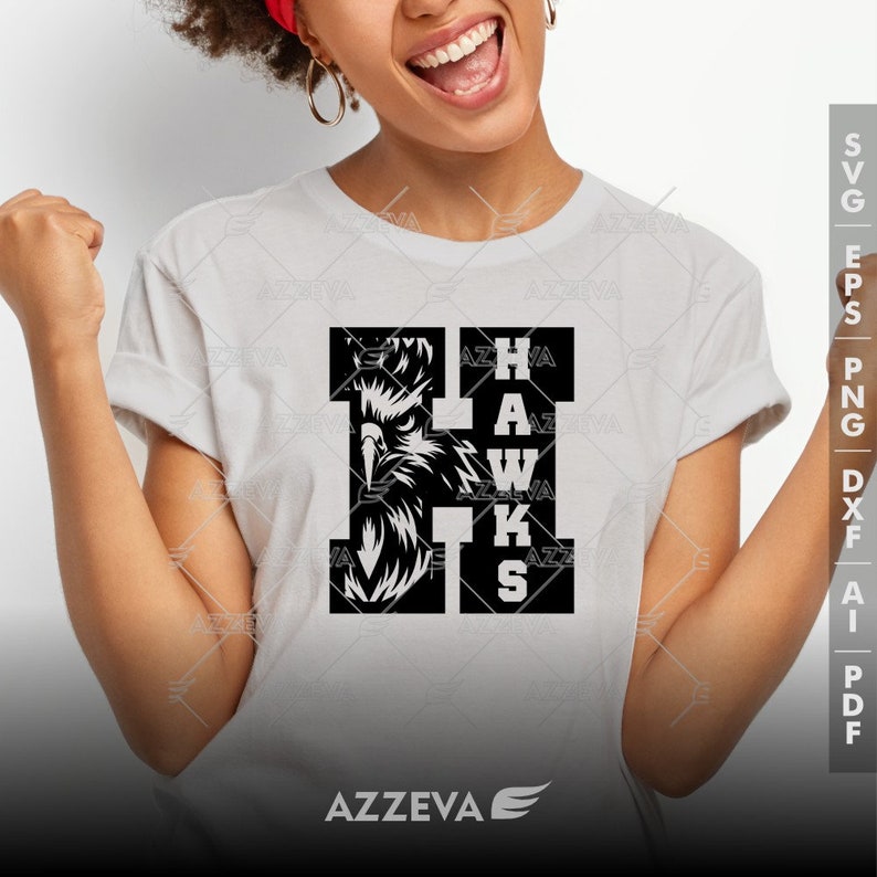 May include: A white t-shirt with a black graphic of an eagle head inside the letter "H" and the word "HAWKS" spelled vertically below. The graphic is on the left side of the shirt.