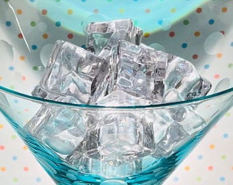 May include: A close-up of a turquoise martini glass filled with ice cubes. The glass has a polka dot pattern.