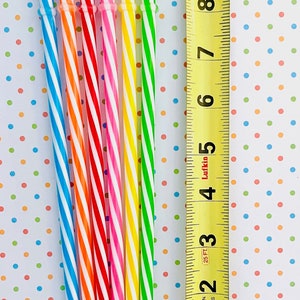 May include: A set of eight striped drinking straws in various colors, including blue, orange, red, pink, yellow, and green. The straws are lined up next to a measuring tape, showing they are approximately 10 inches long.