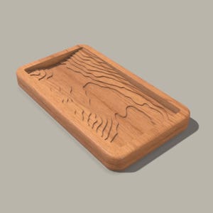 Puede incluir: Una bandeja rectangular de madera con un diseño tallado de líneas onduladas. La bandeja está hecha de madera marrón claro y tiene un acabado liso y pulido.