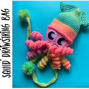 May include: A crocheted squid drawstring bag with a bright pink, yellow, and green color scheme. The bag has a large, colorful pom-pom on the end of the drawstring. The bag is on a blue background.