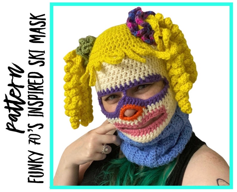 May include: A crocheted ski mask with a colorful face design and yellow hair. The mask has a purple, pink, white, and orange face with a red nose. The hair is styled in two pigtails. The text "FUNKY 70'S INSPIRED SKI MASK Pattern" is on the left side of the image.